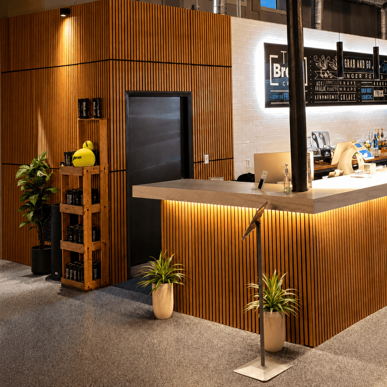 The Tie Break Cafe counter with wood-slat cladding, subway tile, and a lit menu board