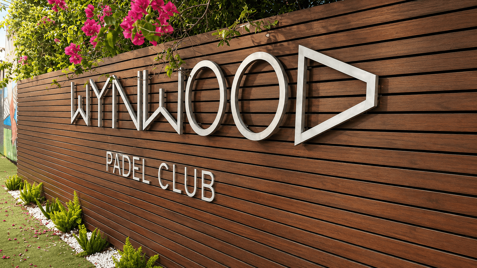 Wynwood Padel Club's wood-slat entrance signage draped in bougainvillea